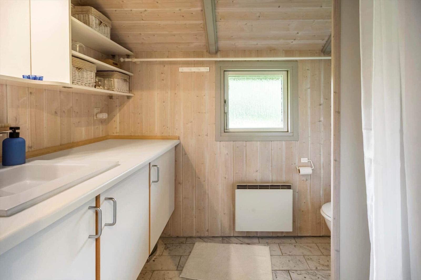 Badezimmer mit Holzwand, Waschbecken und Toilette
