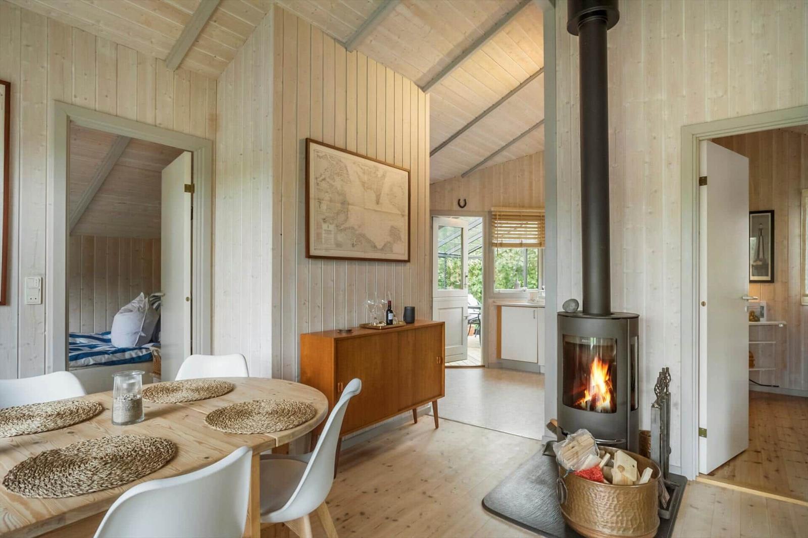 Wohnraum mit Esstisch, Kamin und Blick in Schlafzimmer und Küche.