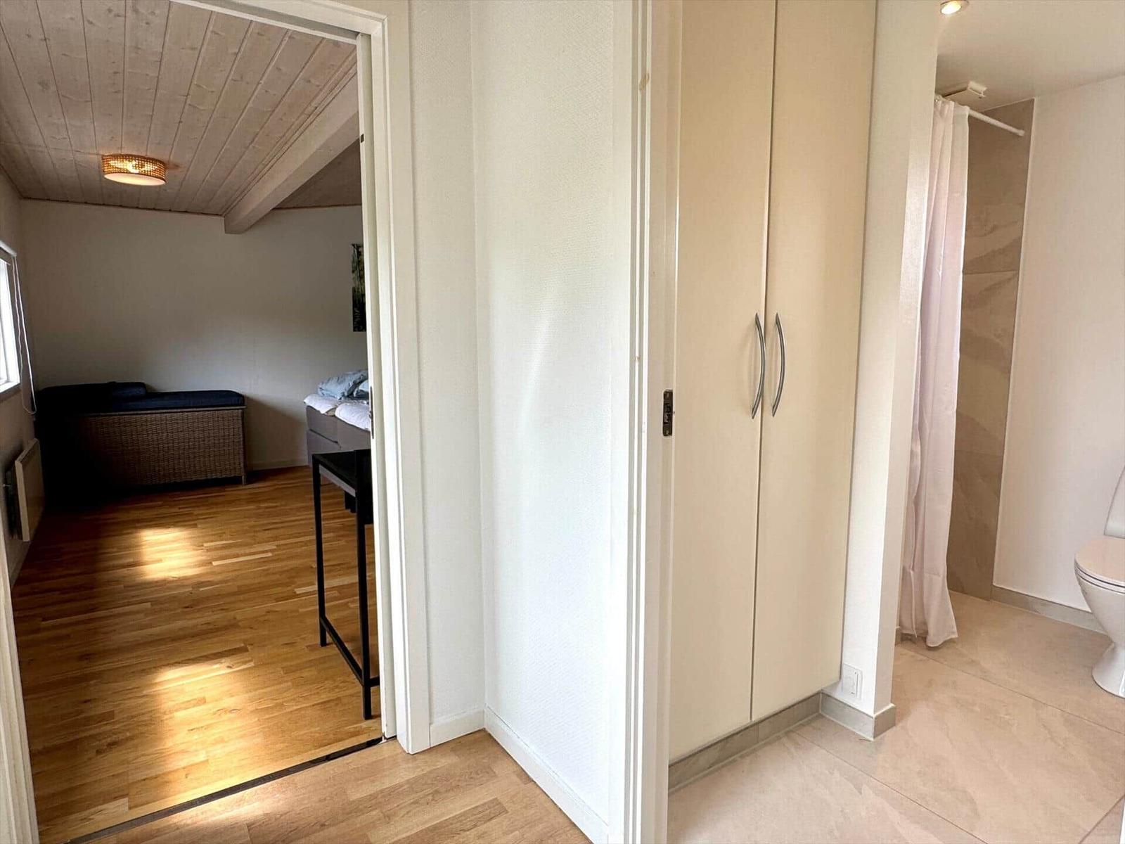 Schlafzimmer mit Holzboden und Dachschrägen. Nebenraum mit Dusche und Toilette.