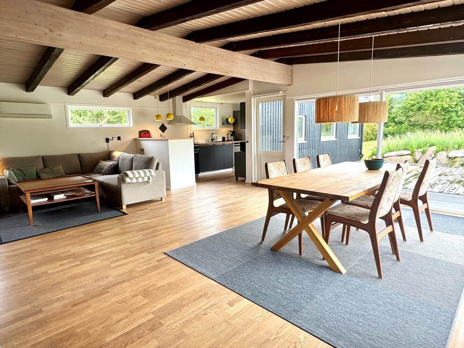Großes Wohn- und Esszimmer mit Holzboden, Esstisch und Blick auf Garten.