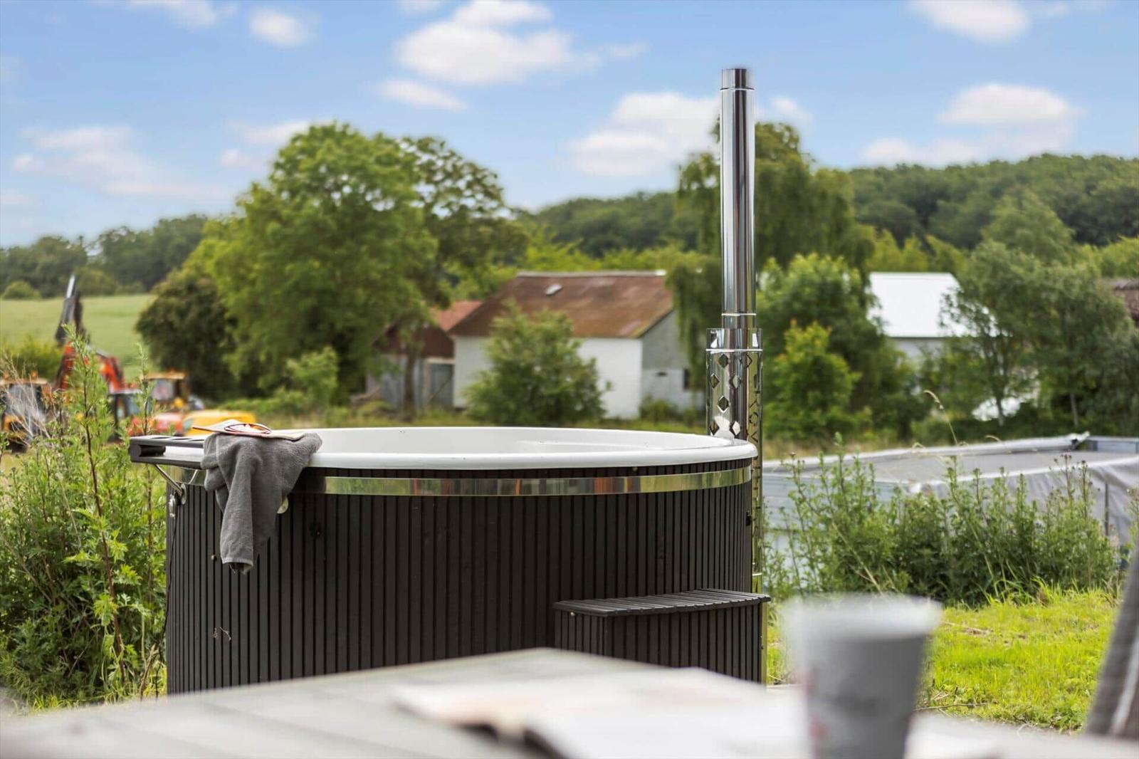 Outdoor hot tub with chimney and view of rural surroundings.