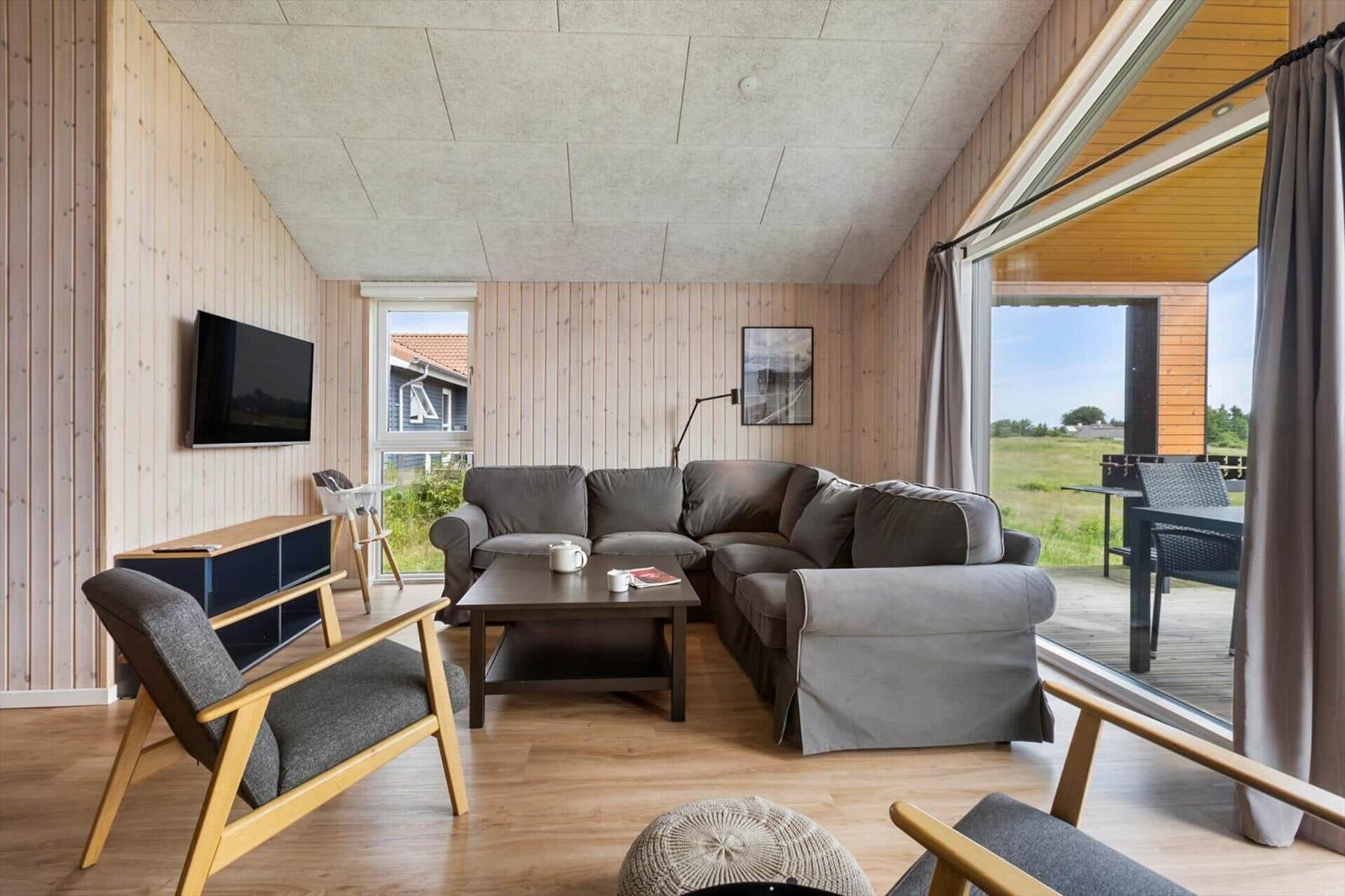 Living room with sofa, TV, and view of the terrace.