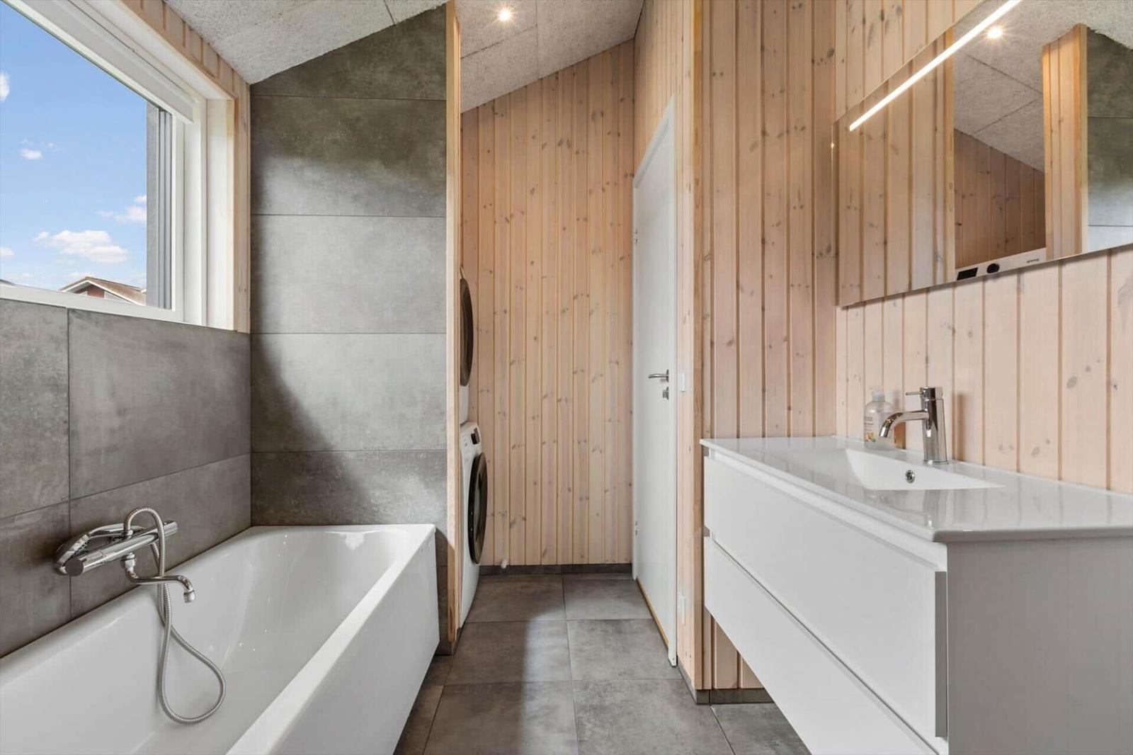 Bathroom with bathtub, washing machine, and mirror cabinet