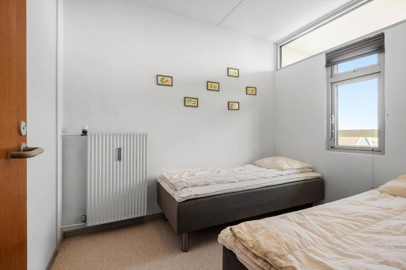 Zimmer mit zwei Betten, Fenster und Heizkörper an der Wand.