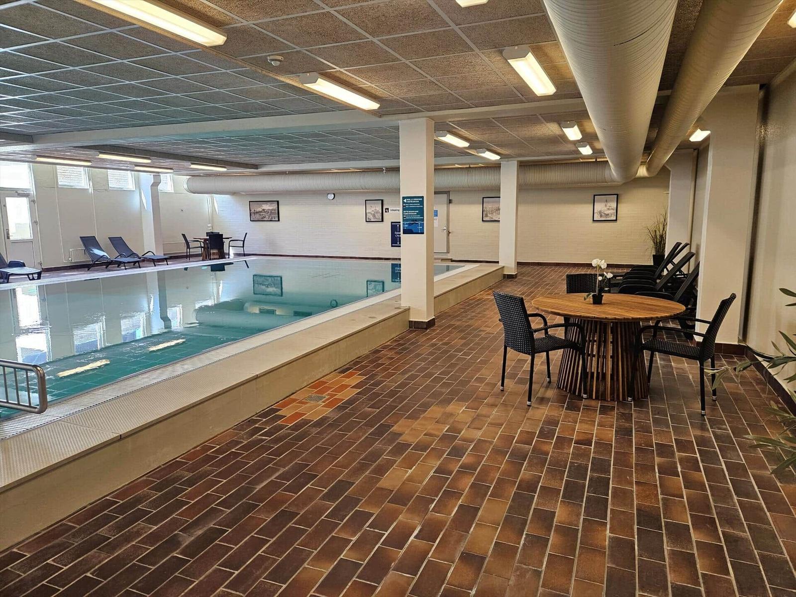 Innenpool mit Liegestühlen und Sitzbereich auf Fliesenboden.