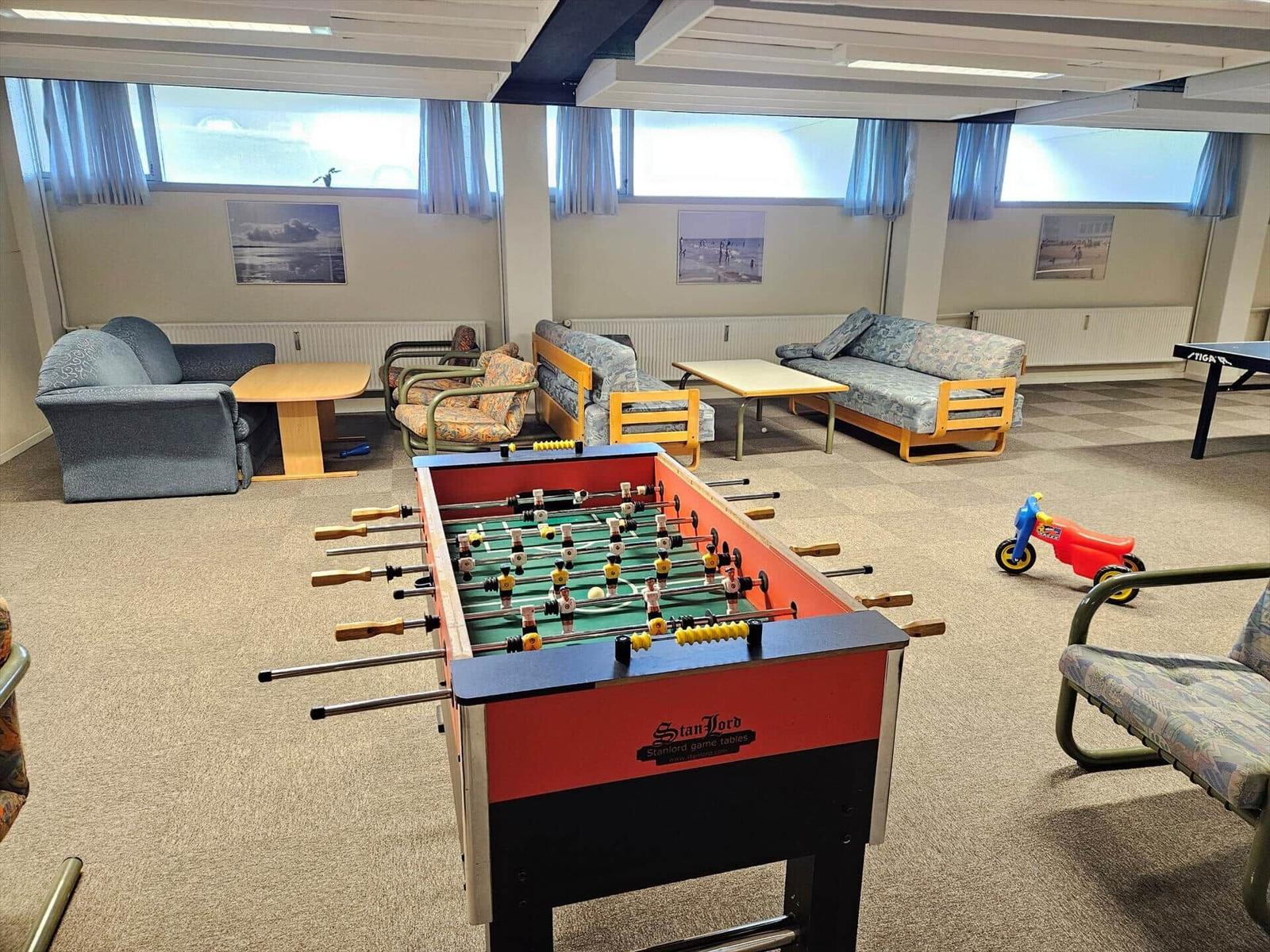 Spielzimmer mit Tischfußball, Sofas und Kinderspielzeug.