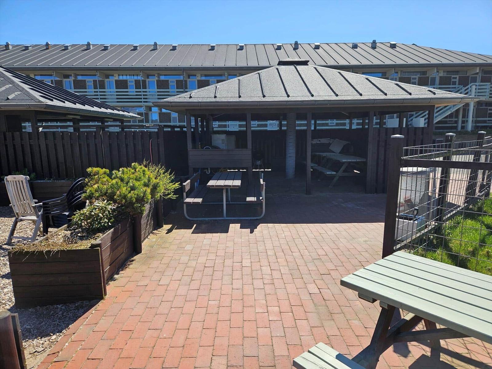 Terrasse mit Pavillon, Tischen und Bechern. Hintergrund: Mehrfamilienhaus.