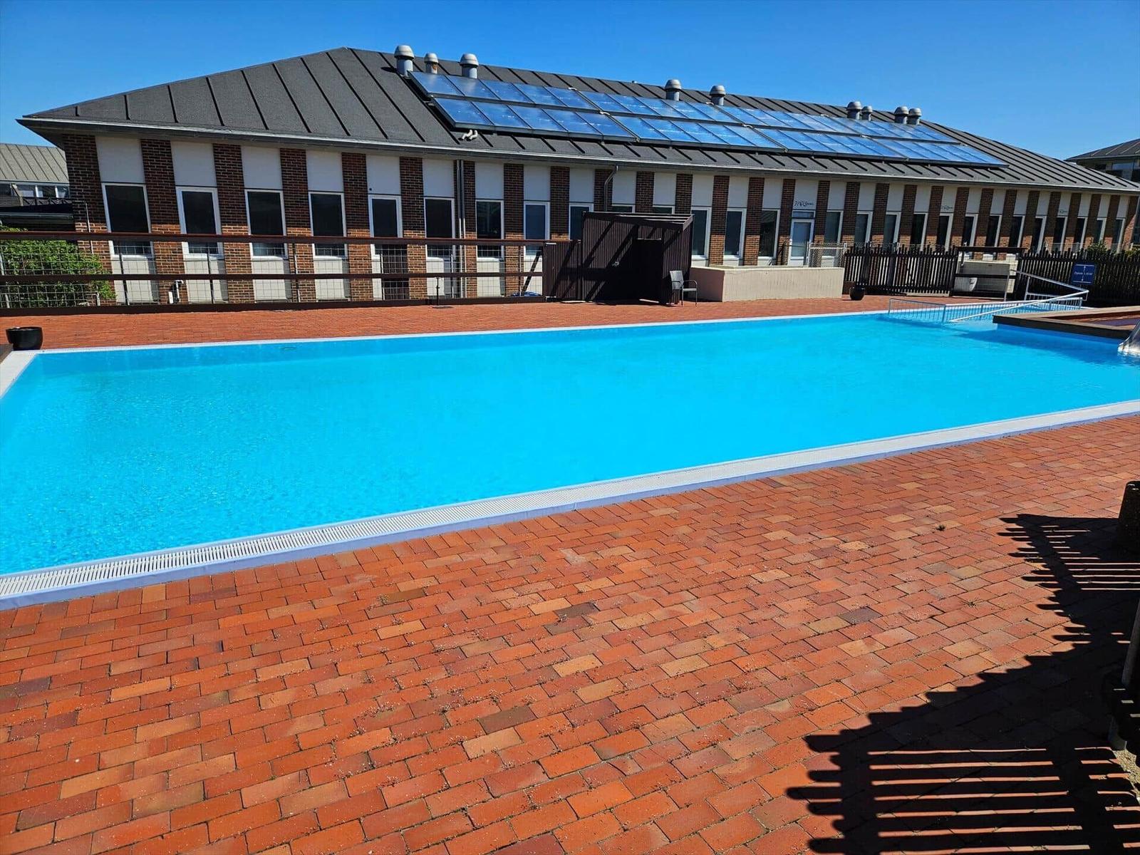 Pool mit rotem Pflaster und Gebäude mit Solarpaneelen auf Dach