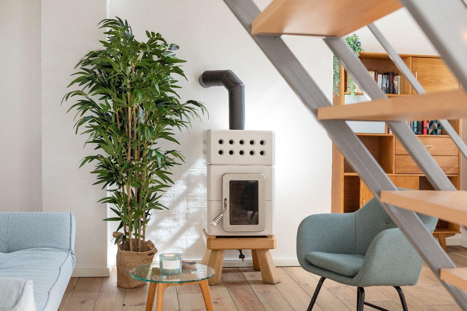 Wohnraum mit Holzstufen, Pflanze, Ofen und Sitzgelegenheiten.