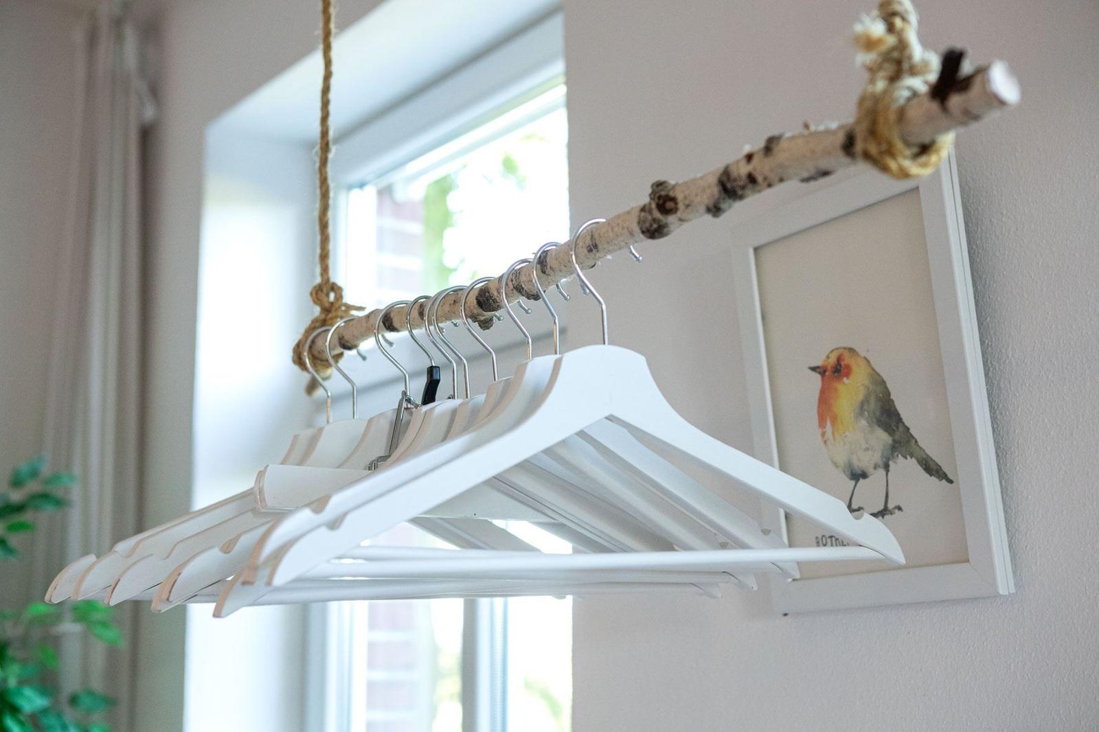 Haken an einem Ast hängen an einem Seil. Ein Bild eines Vogels an der Wand.
