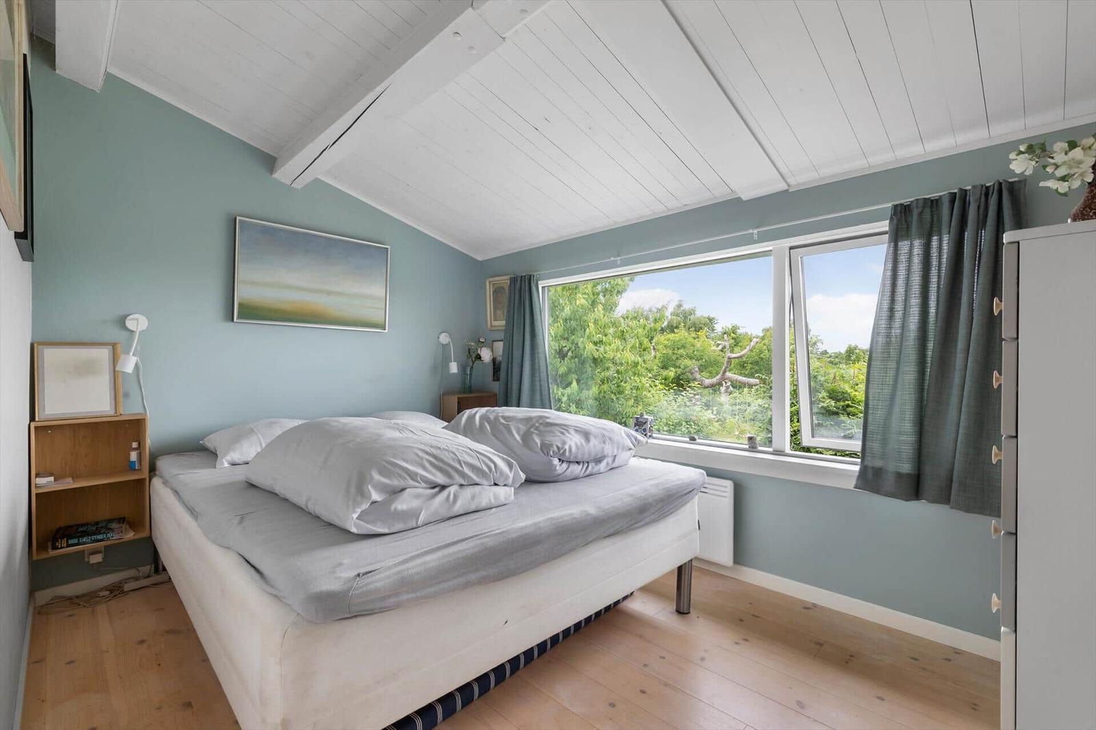 Schlafzimmer mit Bett, Fenster und Holzboden.