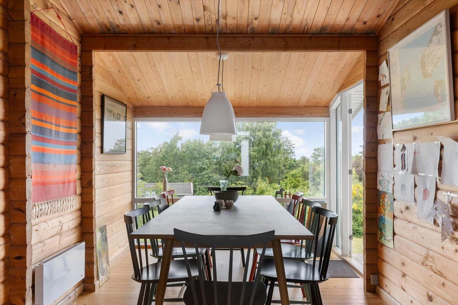 Esszimmer mit Holzwand, Tisch und Stühlen, Blick auf Garten
