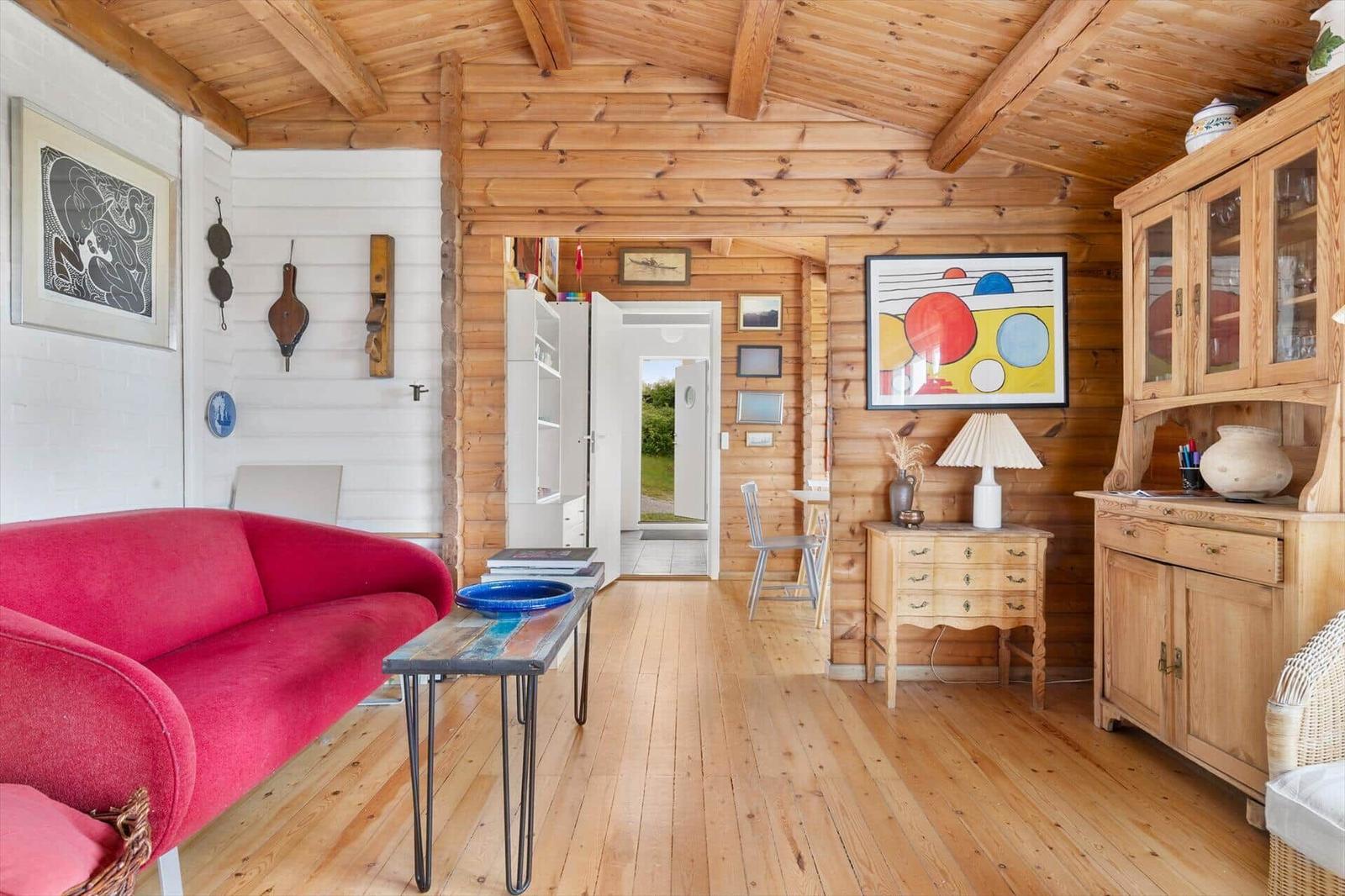 Ein Wohnzimmer mit Holzdecke, rotem Sofa und Holzmöbeln.