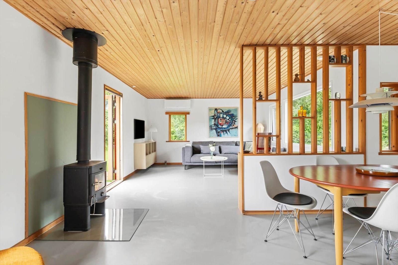 Living space with wooden ceiling, fireplace, sofa, and dining area with table and chairs.