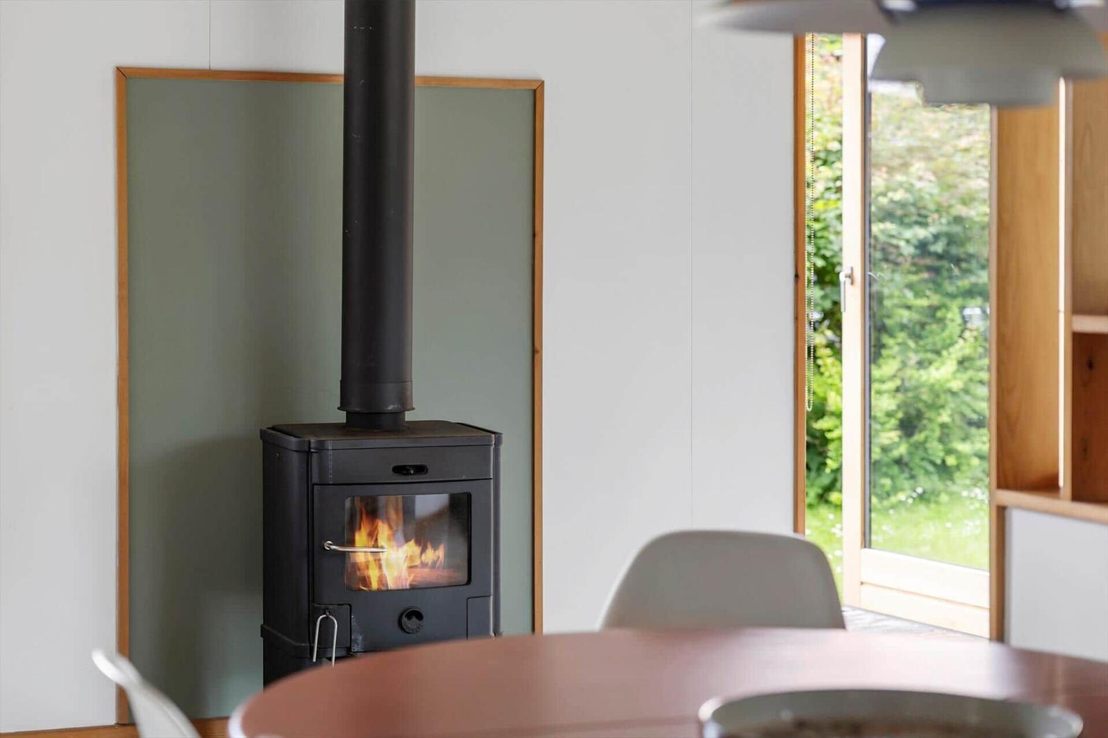 Wood stove with burning fire in a room with window and table