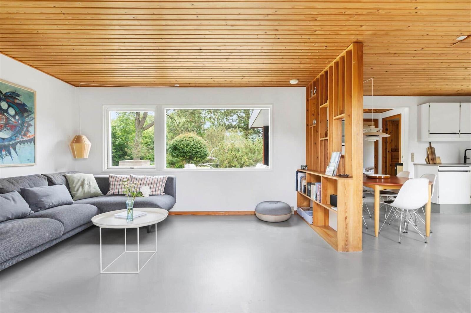Living room with sofa, table, and bookshelf. Kitchen and terrace are visible.