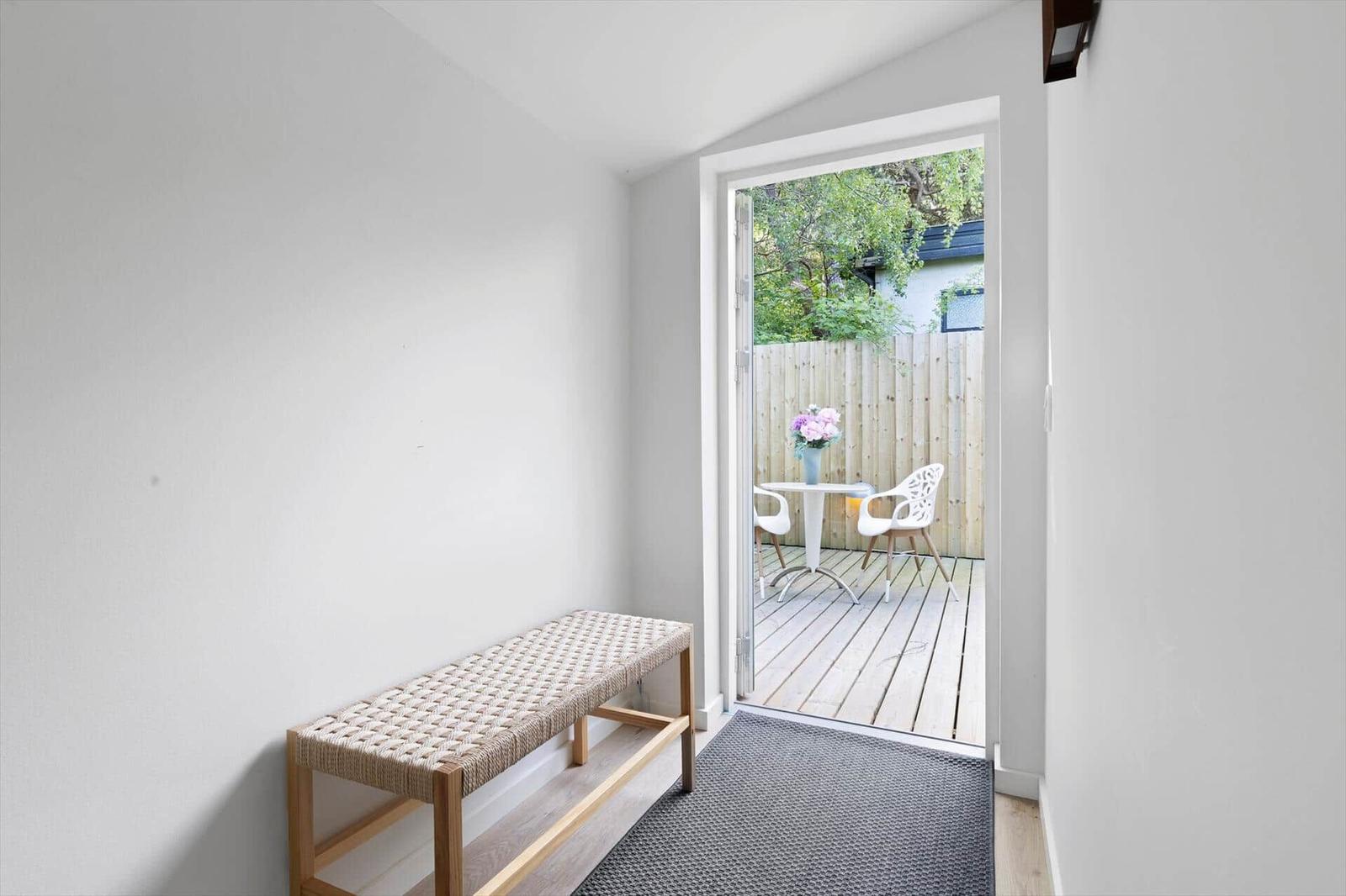 Entrance area with bench and door to balcony with table and chairs.