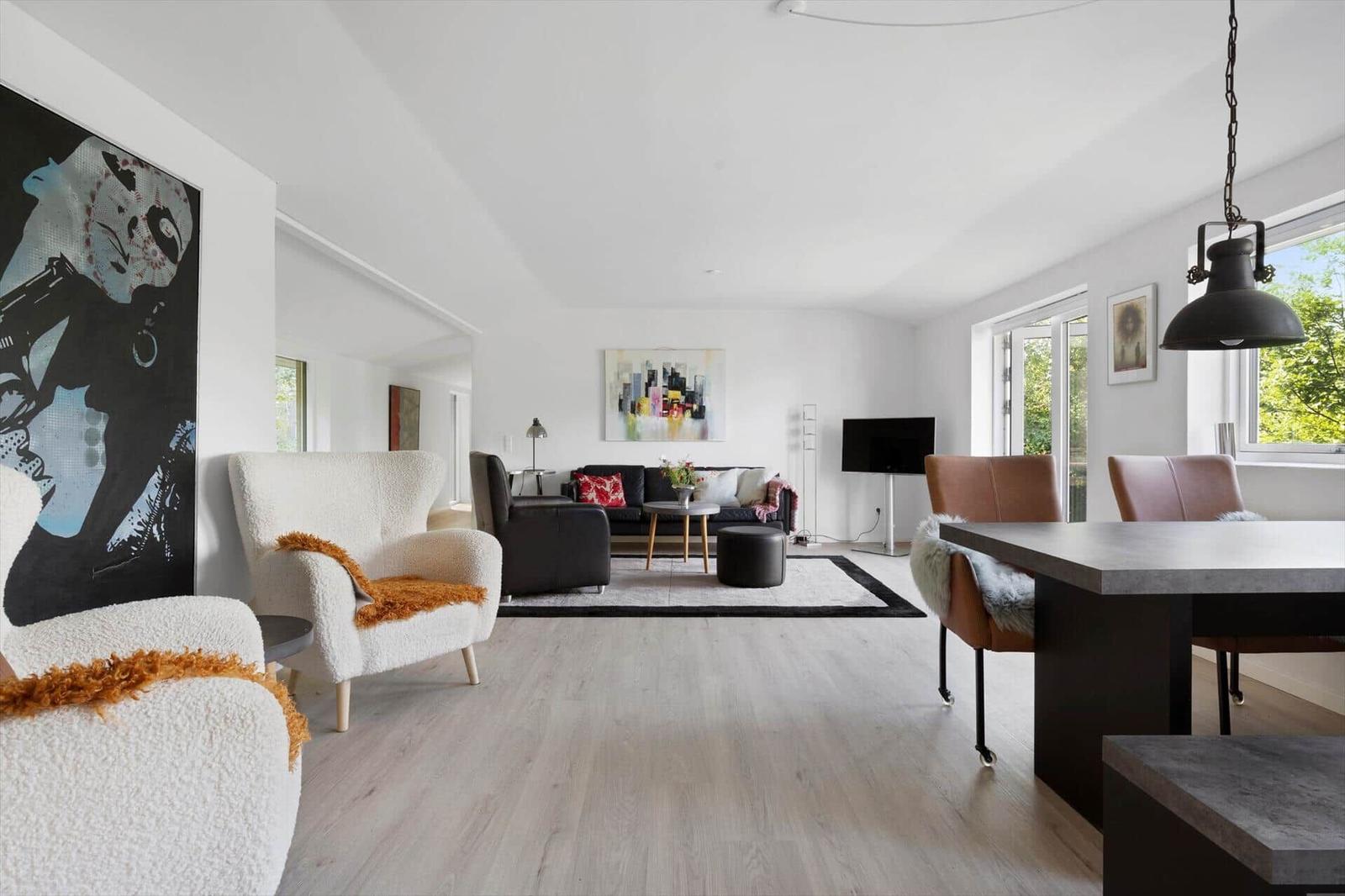 Living and dining area with modern furniture and large windows.
