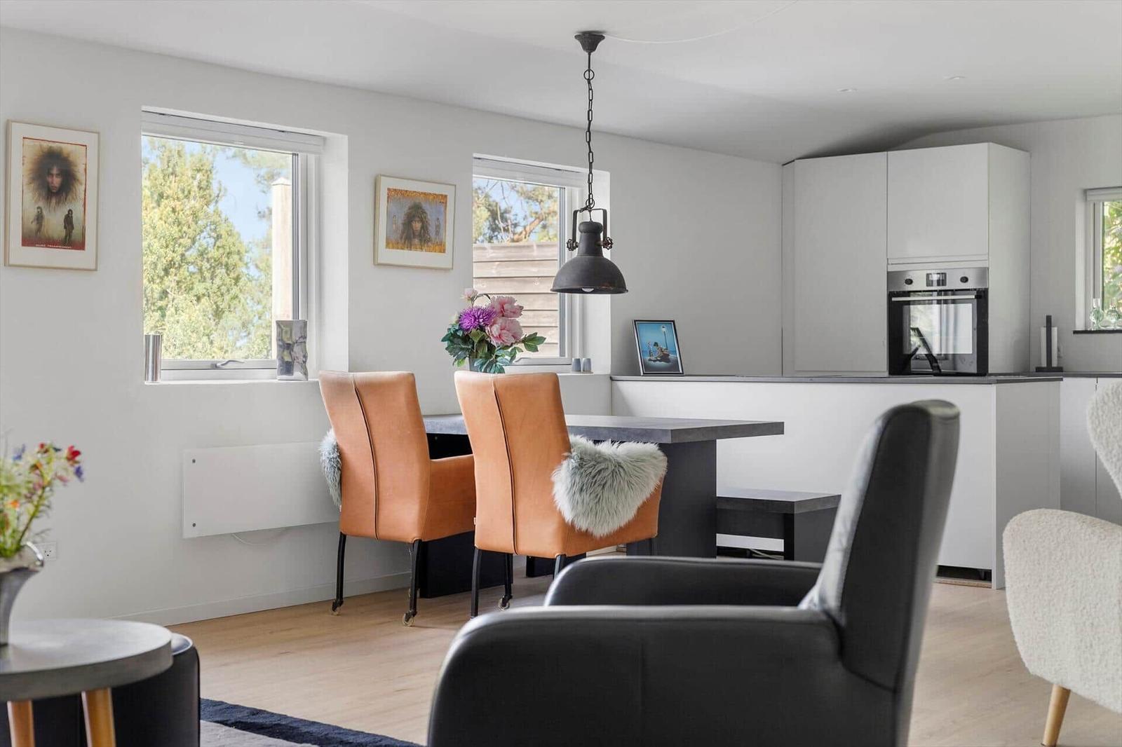 Kitchen and dining area with brown chairs, windows, and modern lighting.