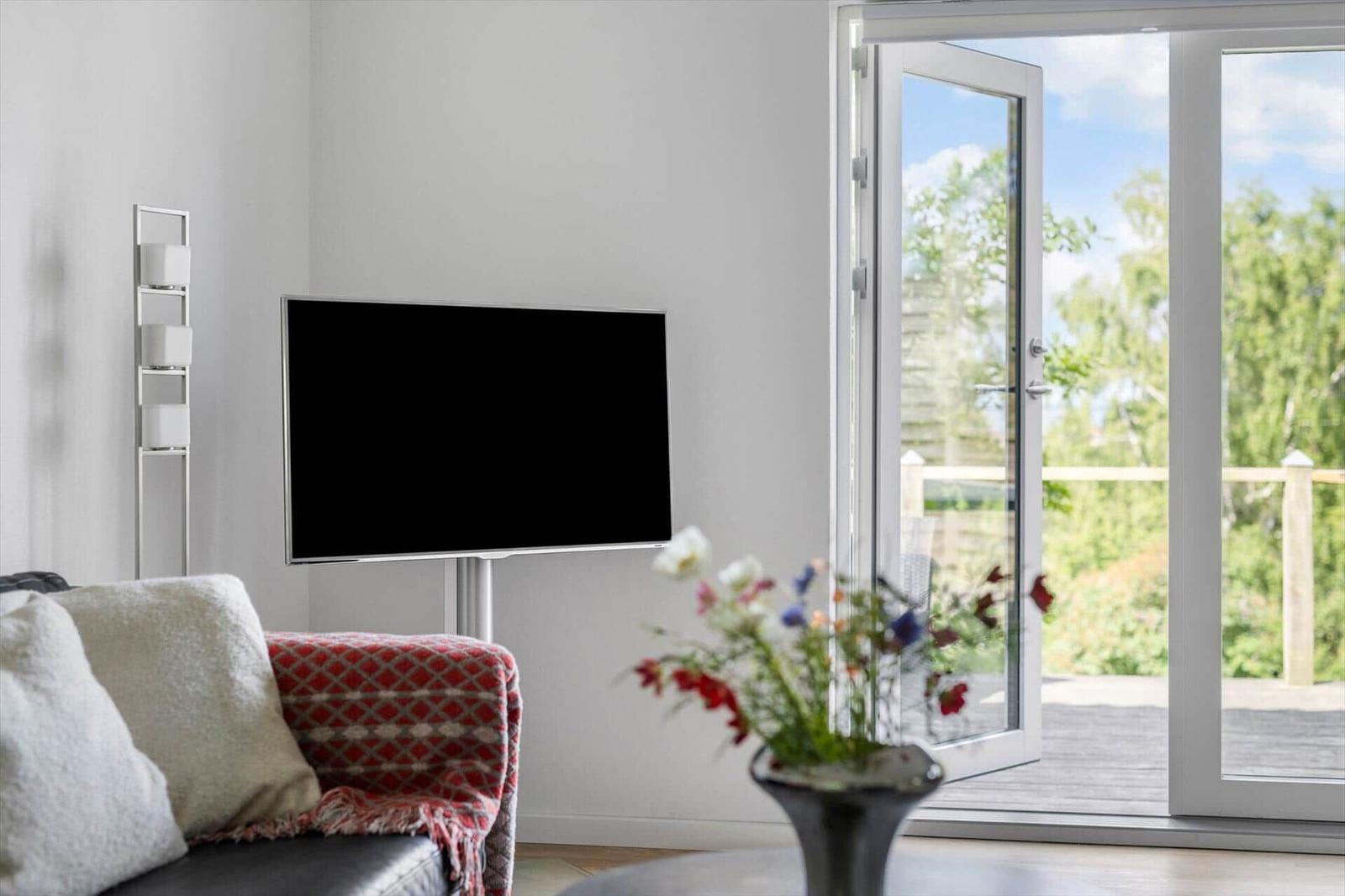 A living room with a TV, sofa, and view of the terrace.