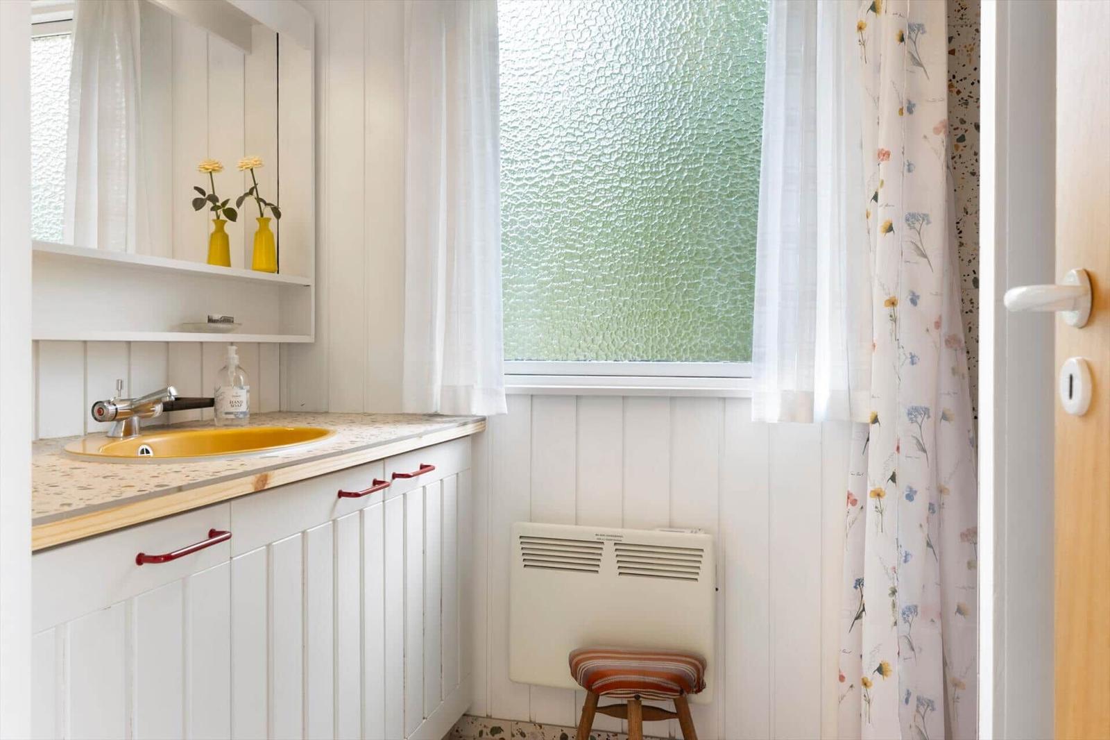 Bad mit Waschbecken, Spiegelschrank und Fenster mit Glastüren.