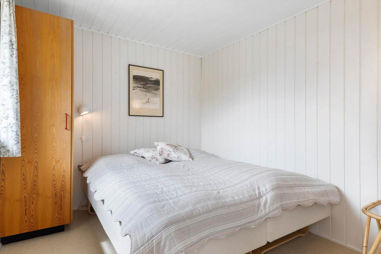 Schlafzimmer mit Bett, Kleiderschrank und Wandbild.