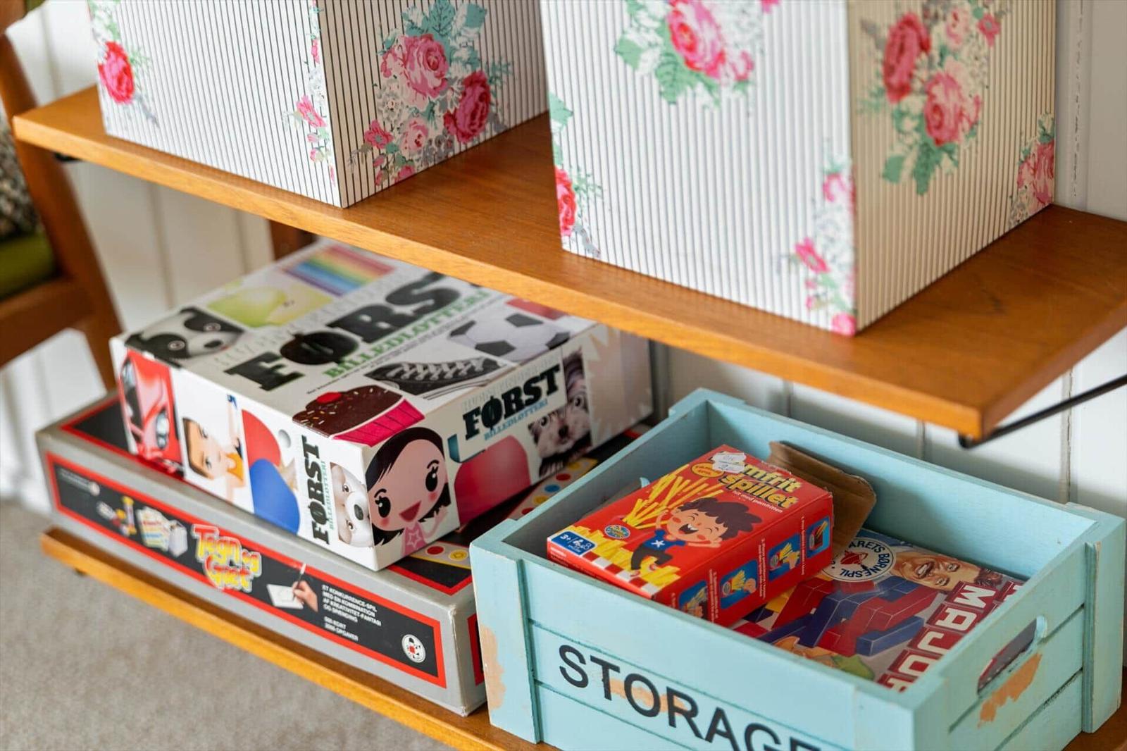 Holzregal mit Spielzeugboxen und floralen Aufbewahrungskisten.