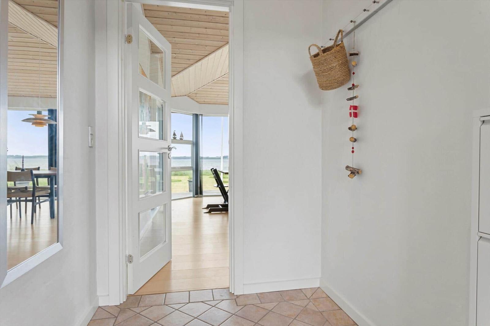 Hallen mit Holzdecke und Blick auf Wasser. Wand mit Korb und Dekoration.