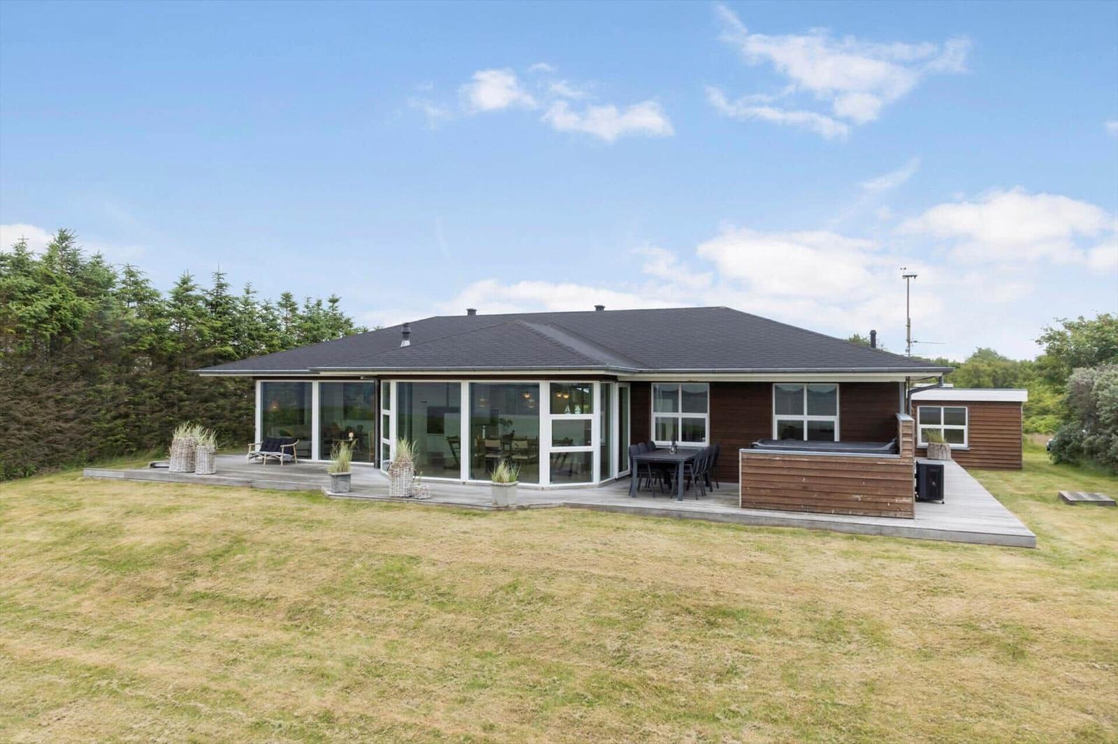 Moderne Villa mit großem Garten und Terrasse mit Sitzgelegenheiten.