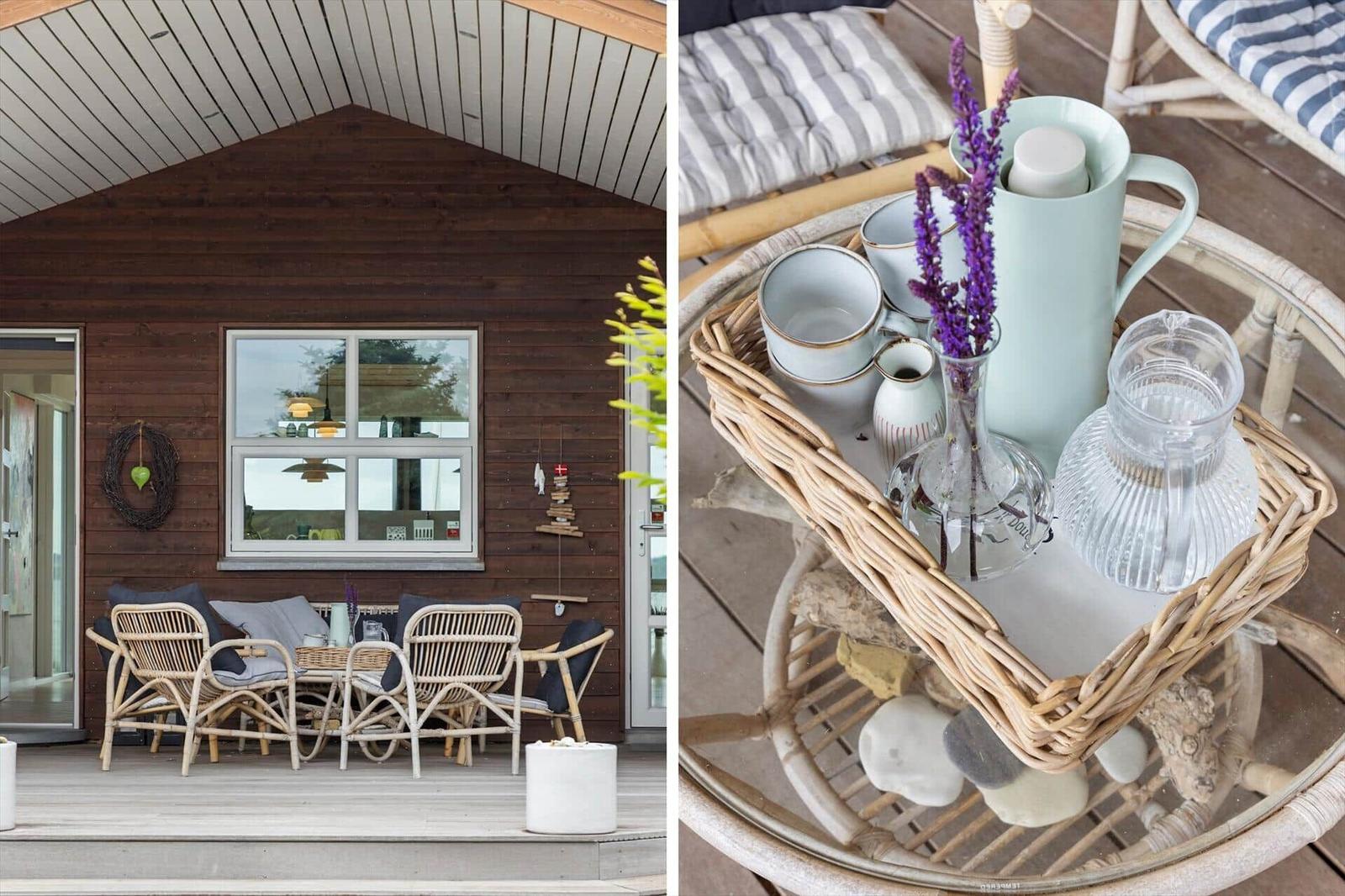 Terrasse mit Rattanmöbeln und Holzwand. Tisch mit Teekannen und Lavendel.