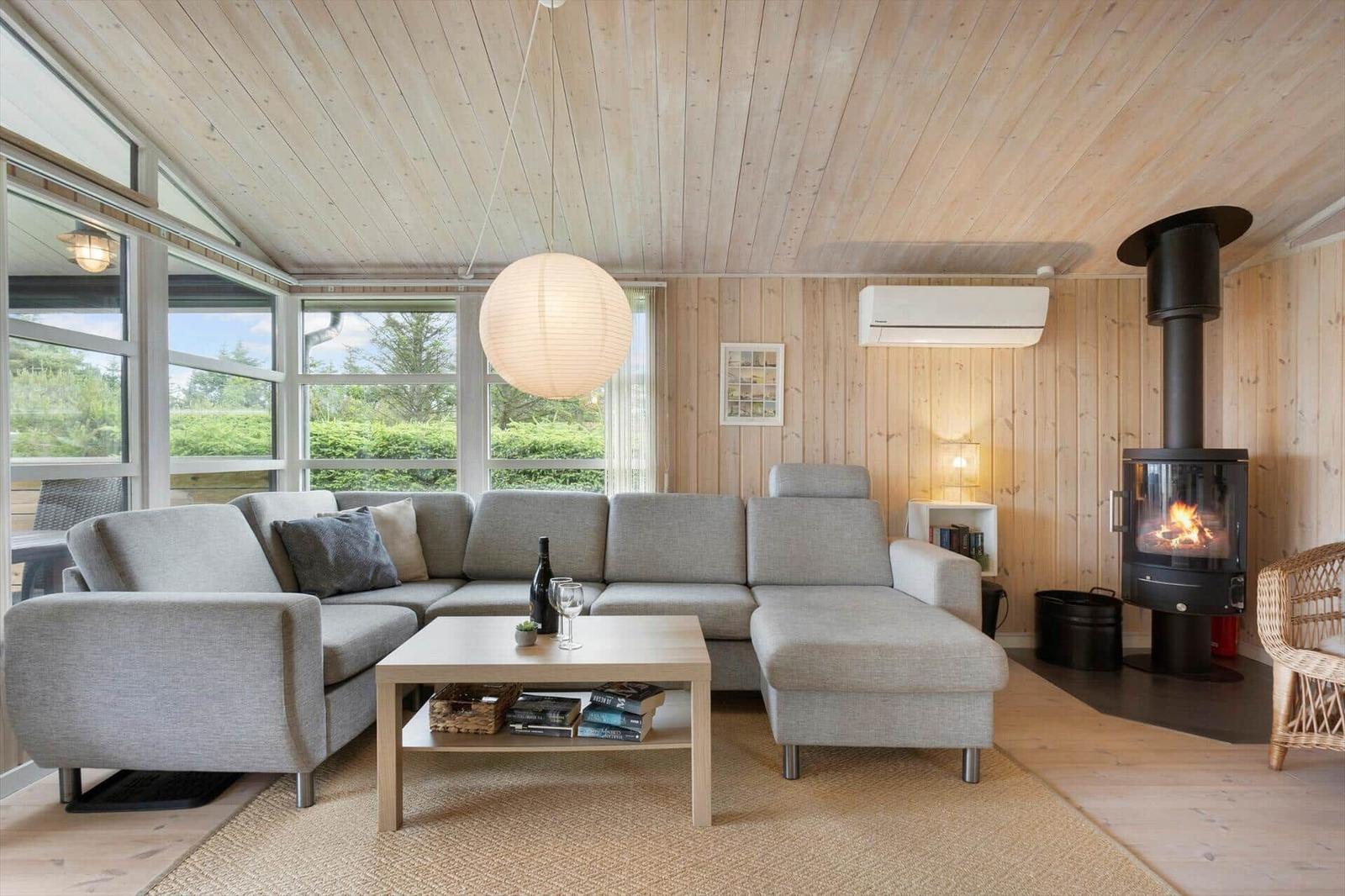 Wohnzimmer mit Sofa, Kamin und großen Fenstern.
