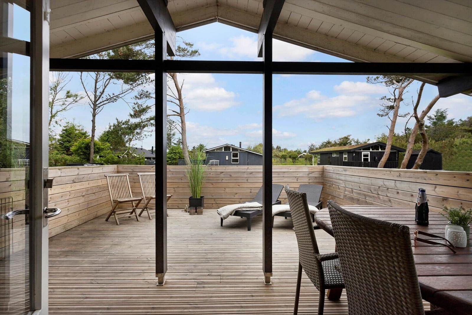 Terrasse mit Sitzgelegenheiten und Blick auf Wald und Häuser