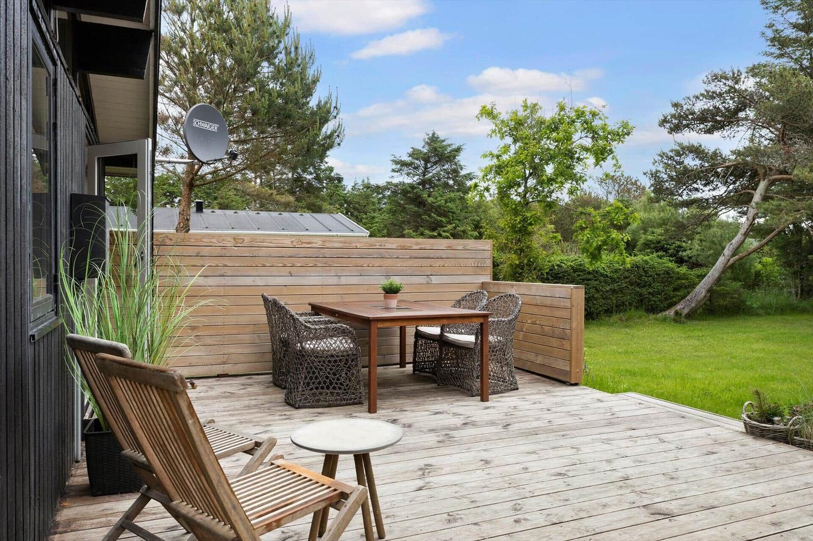 Terrasse mit Holztisch, Stühlen und Gartenansicht.