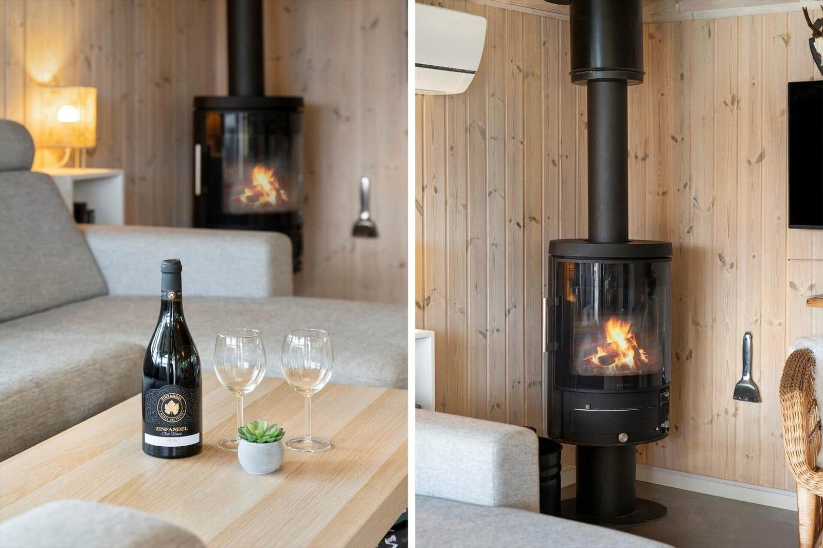 Wohnzimmer mit Kaminofen, Couch und Tisch mit Wein und Gläsern.