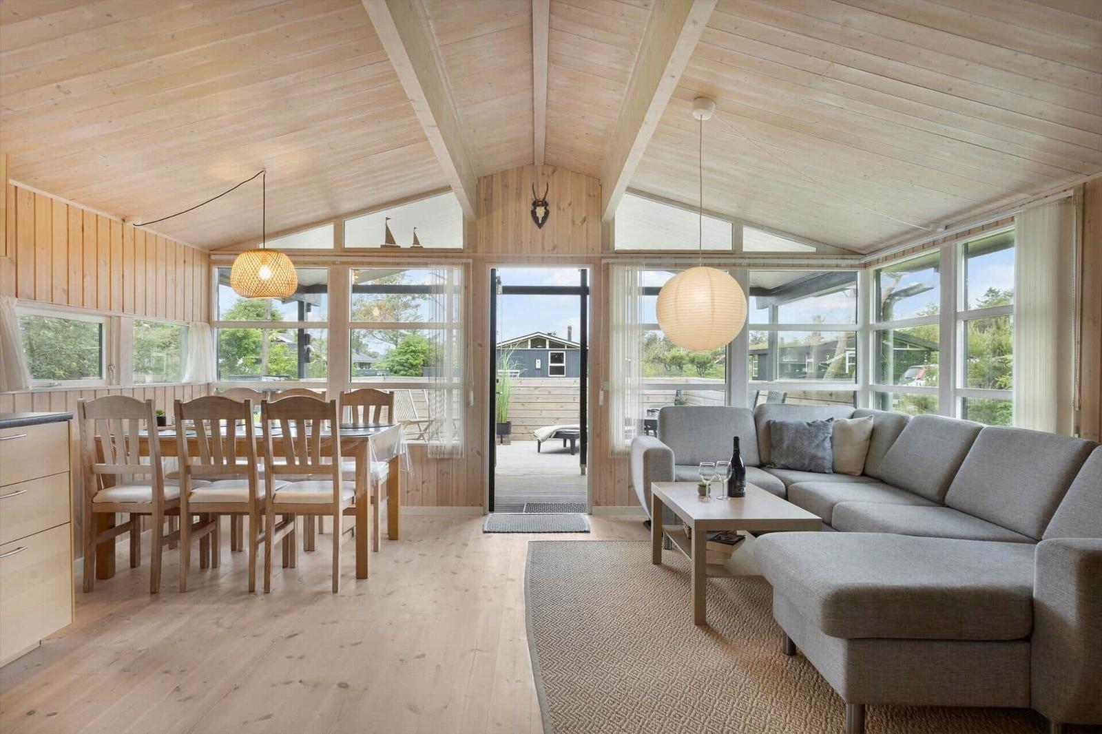 Wohn- und Essbereich mit Holzdecke, Sofa und Tisch mit Stühlen.