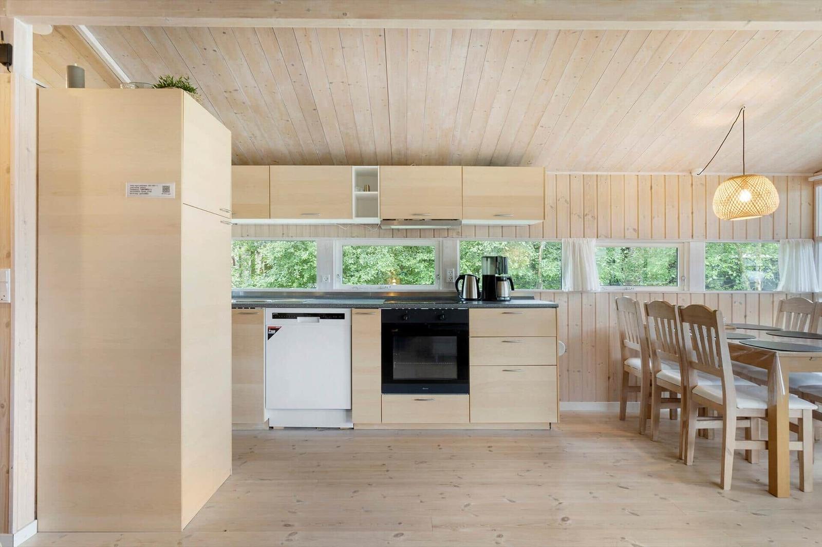Küche mit Essbereich, Holzelemente und Fenstern zur Natur