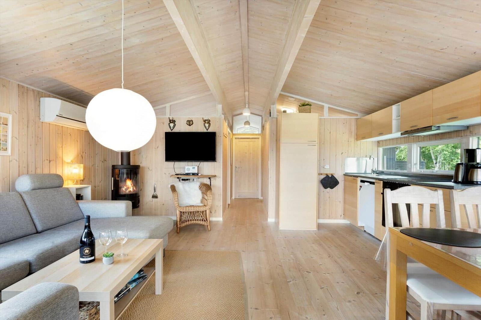 Wohnung mit Holzdecke, Kamin, Sofa, TV und Küche.