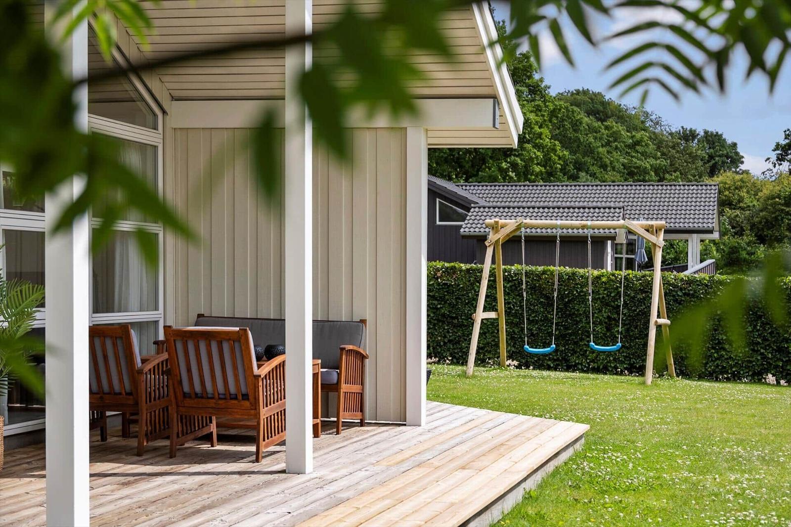Deck with wooden furniture and swing in the garden