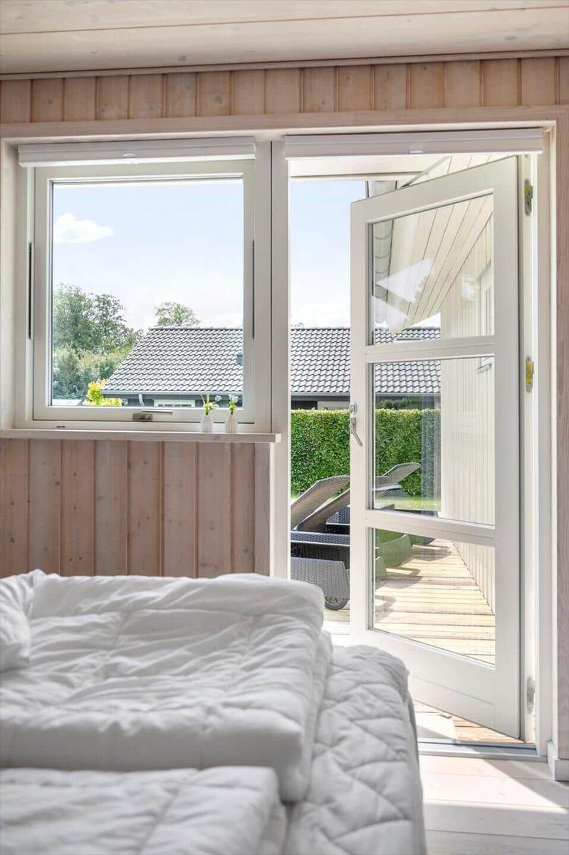 Bedroom with view of terrace and garden. Door and window are open.