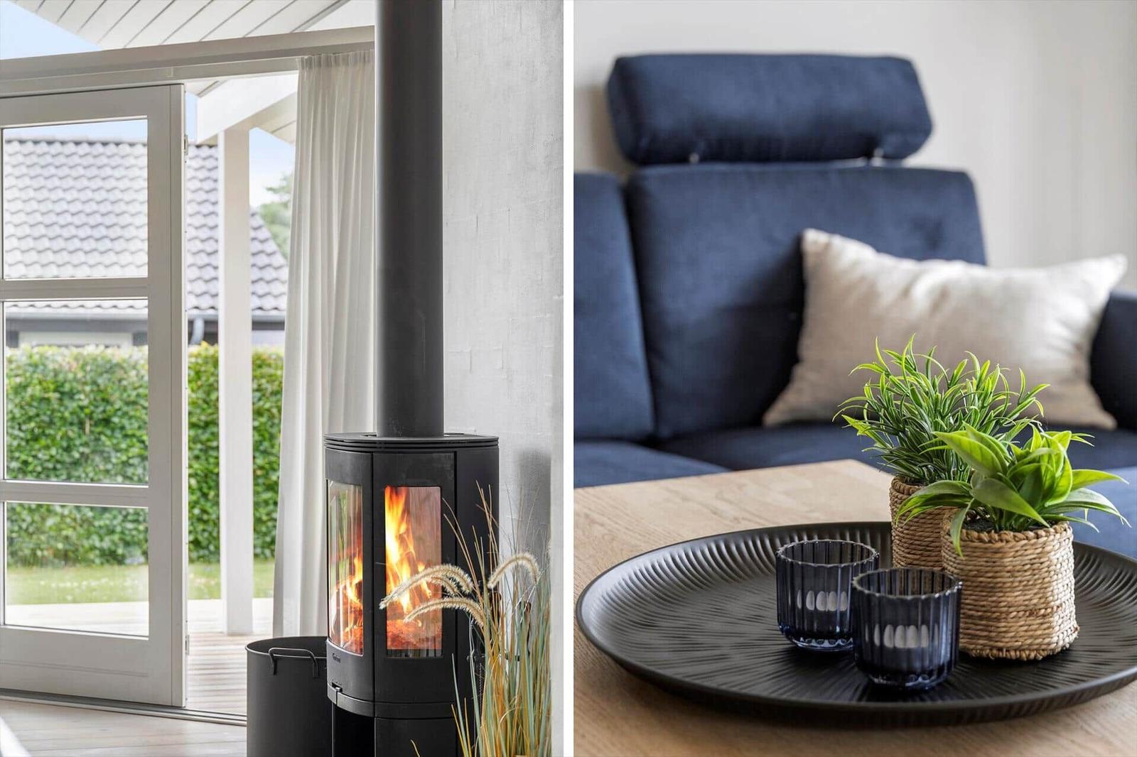 Wood-burning stove with view to terrace. Sofa with cushions and plant on table.