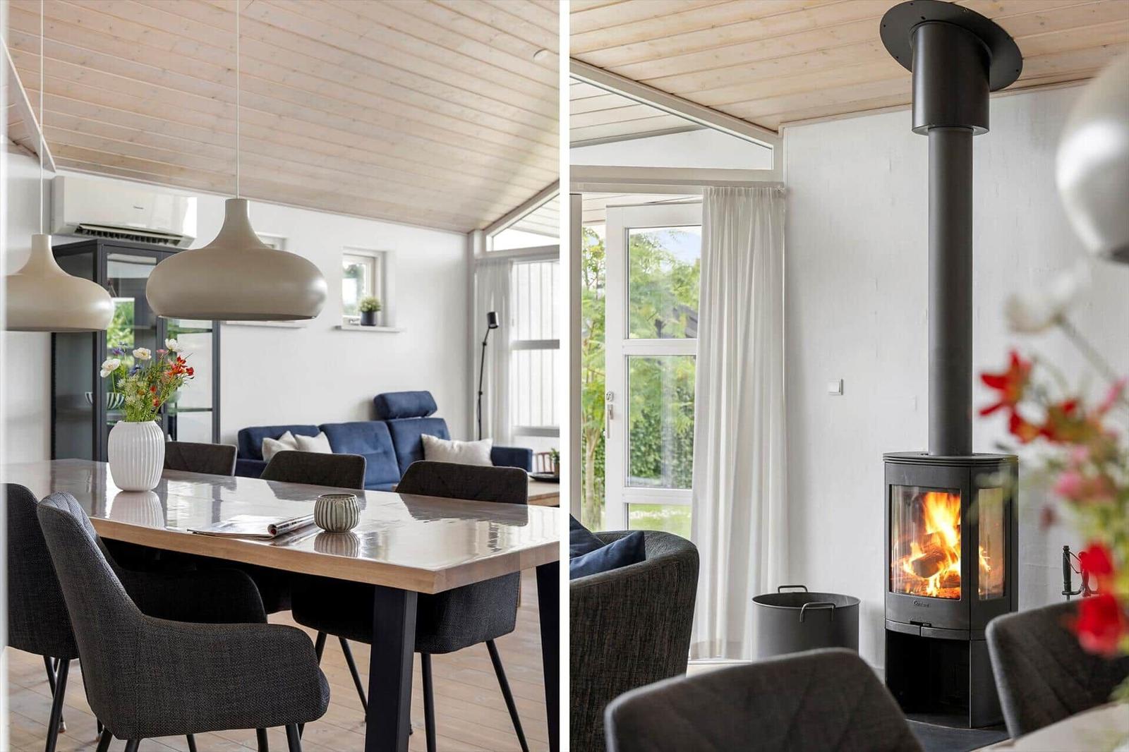 Dining area with table and chairs, wood-burning stove, and windows overlooking outside.