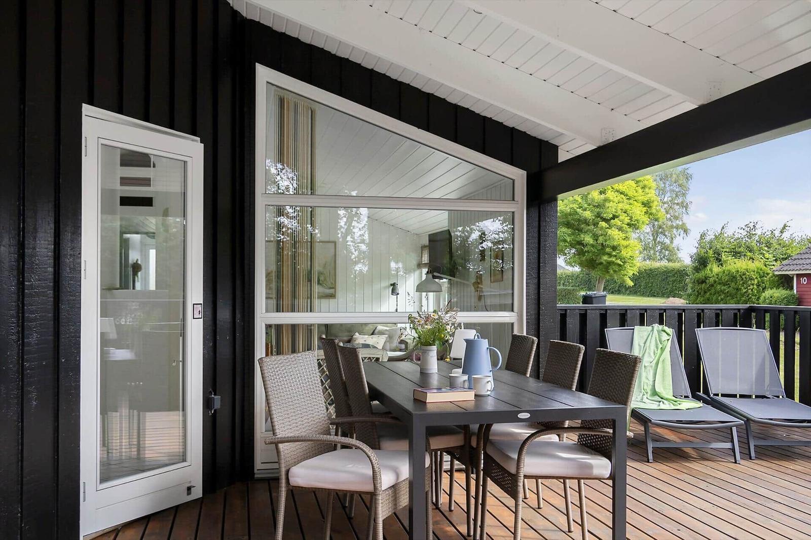 Deck with dining table, chairs, and loungers. Door and large window to interior.