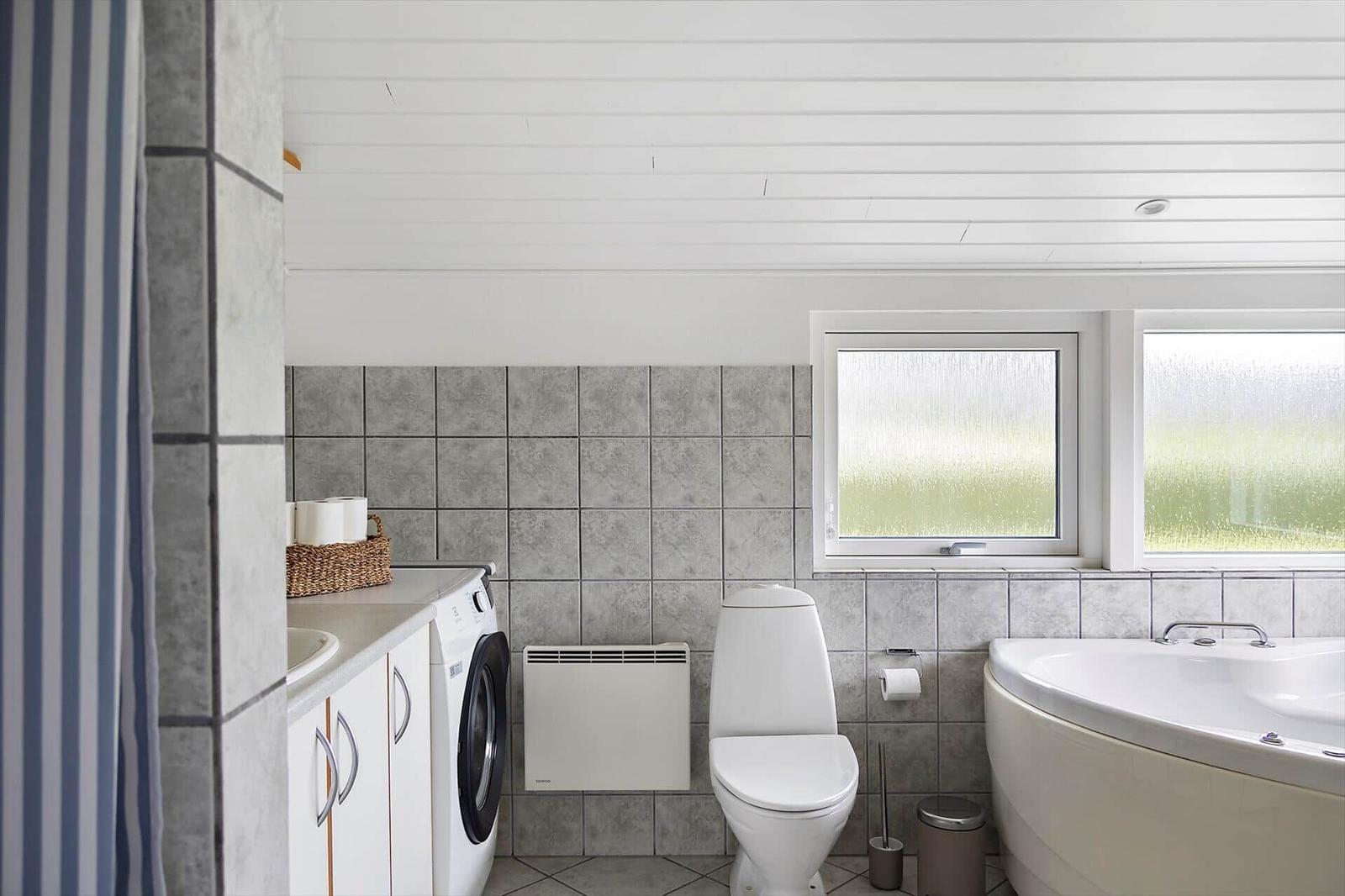 Bathroom with bathtub, toilet, washing machine, and windows with frosted glass.