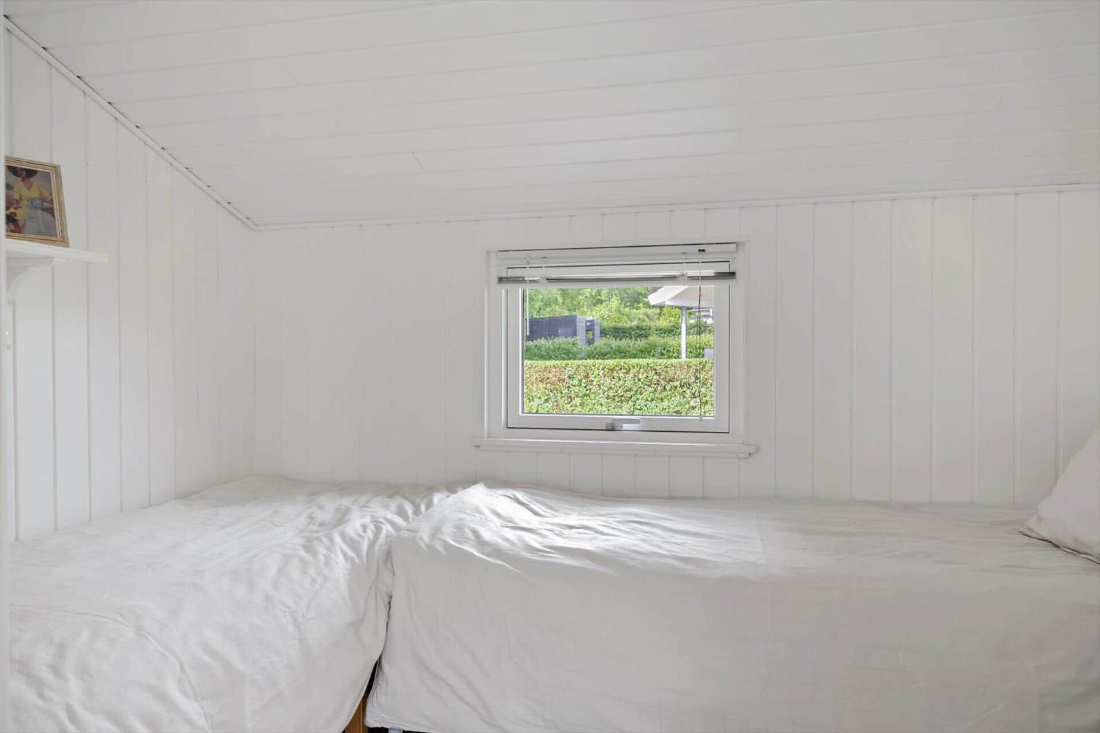 Room with two beds and window view of green area