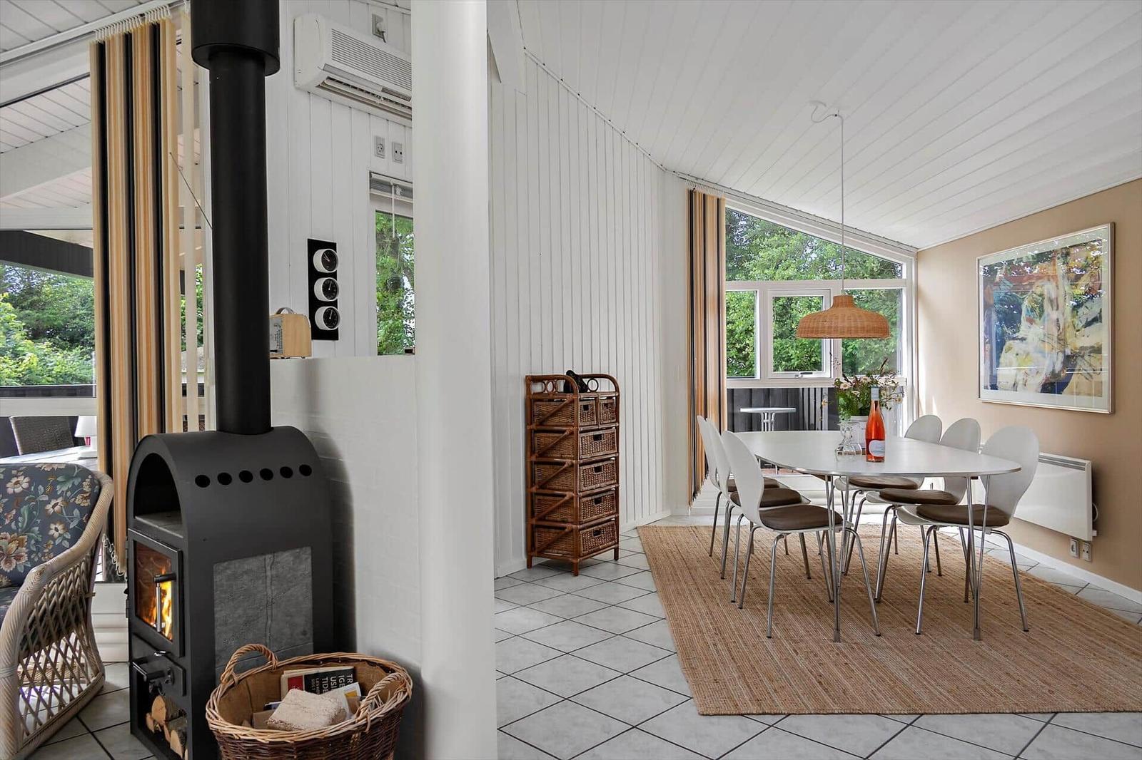 Dining area with table, chairs, and window. Next to it stands a wood stove.