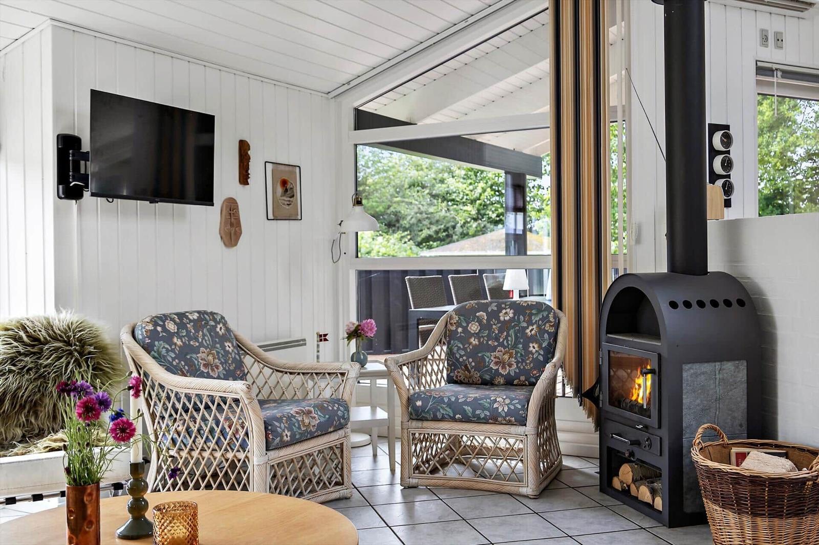 Living room with two chairs, wood stove, and TV mounted on the wall.