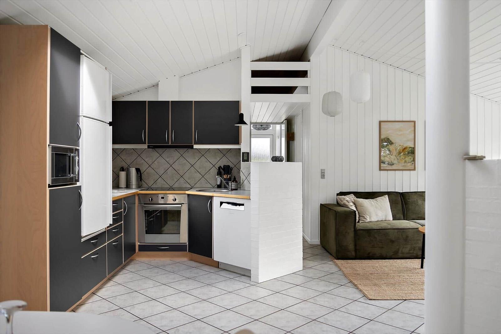 Kitchen with black cabinets and living area with green sofa.