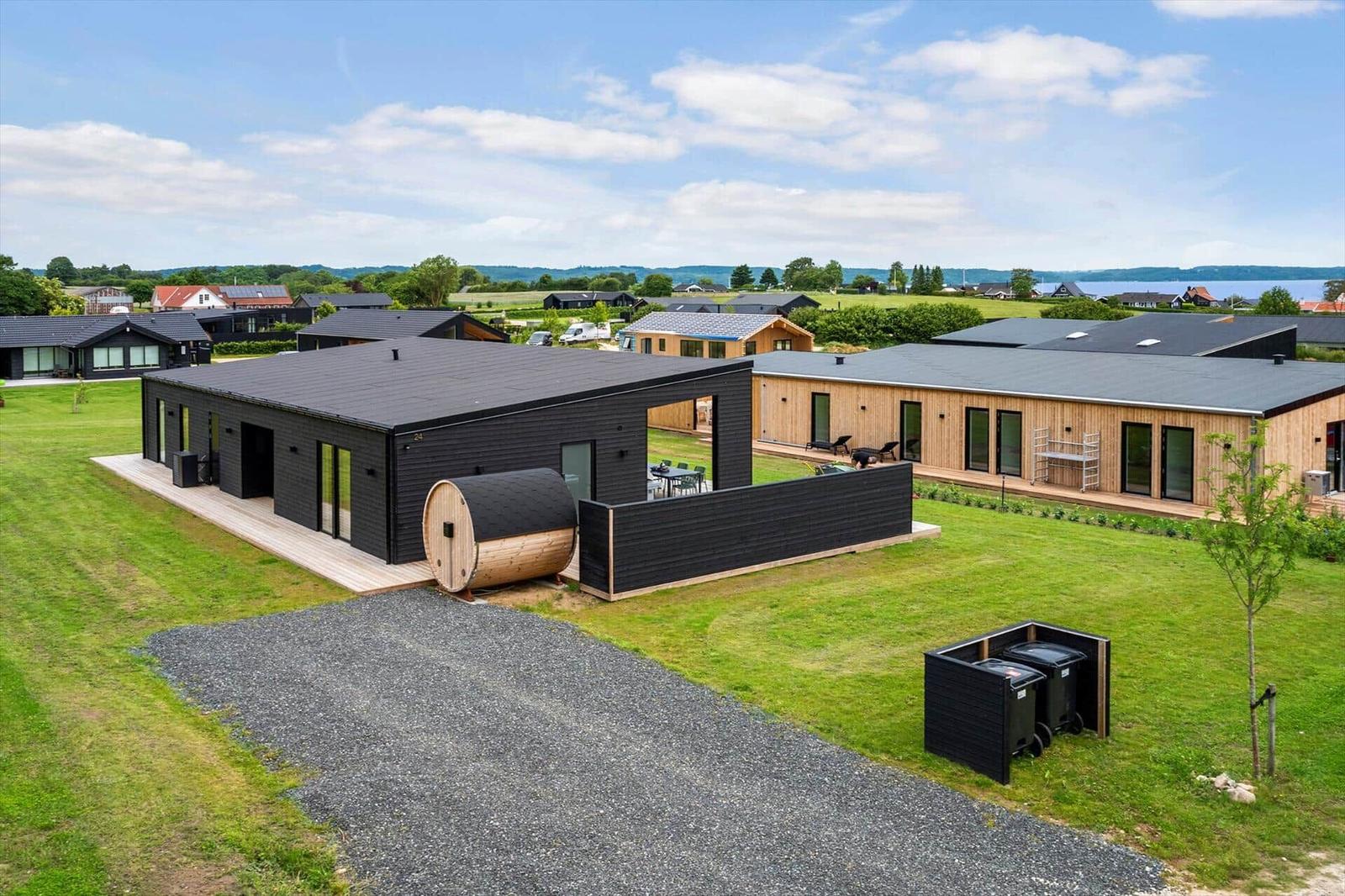 Moderne Holzhäuser mit Terrassen und Sauna im Grünen. Blick auf See und Landschaft.