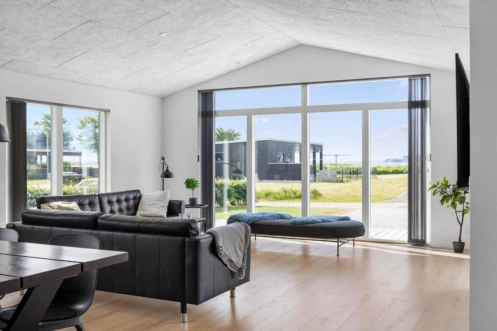 Living room with black leather sofa, wooden floor, and large windows for views.