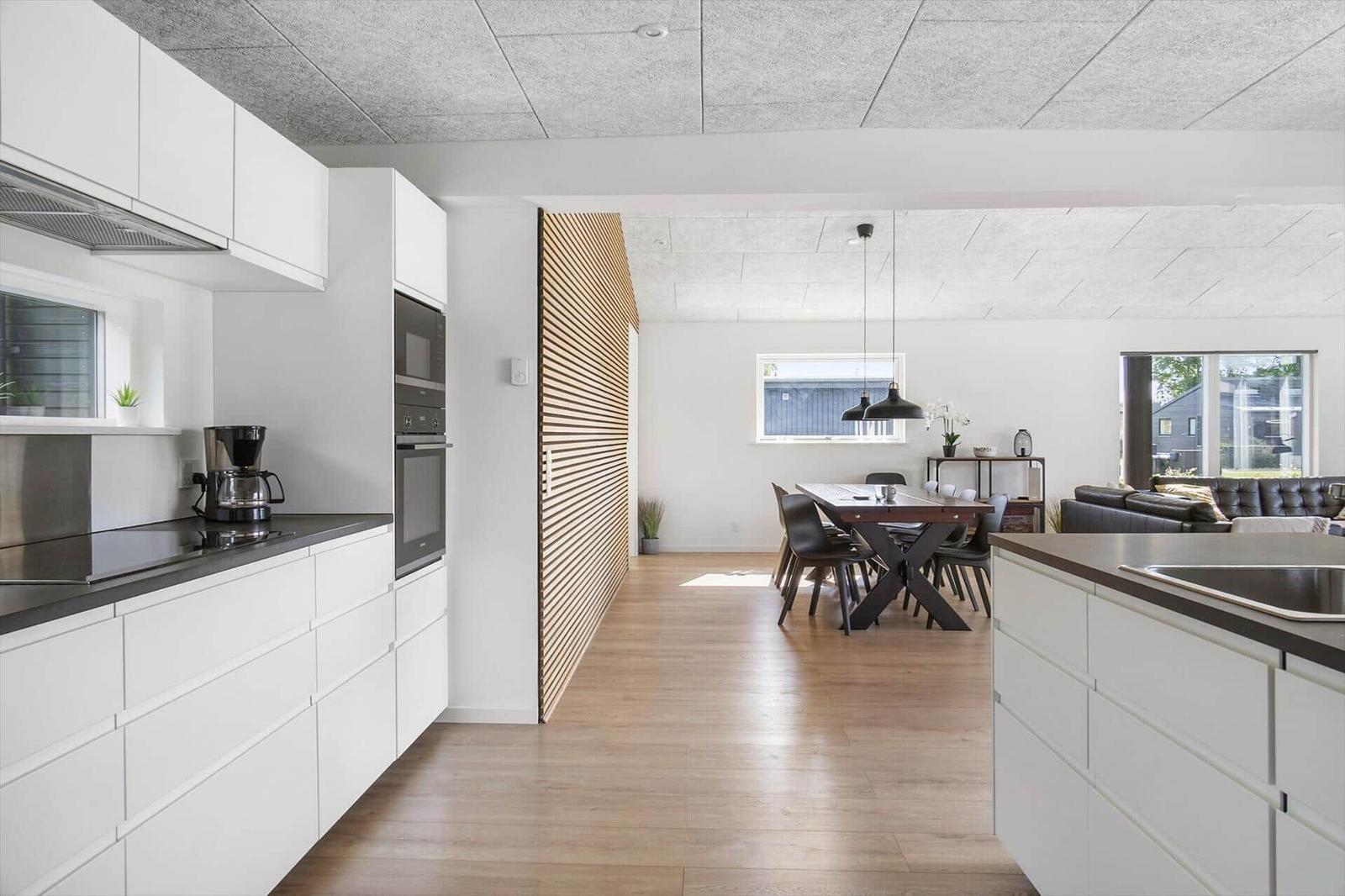 Modern kitchen with dining area and living room in the background.